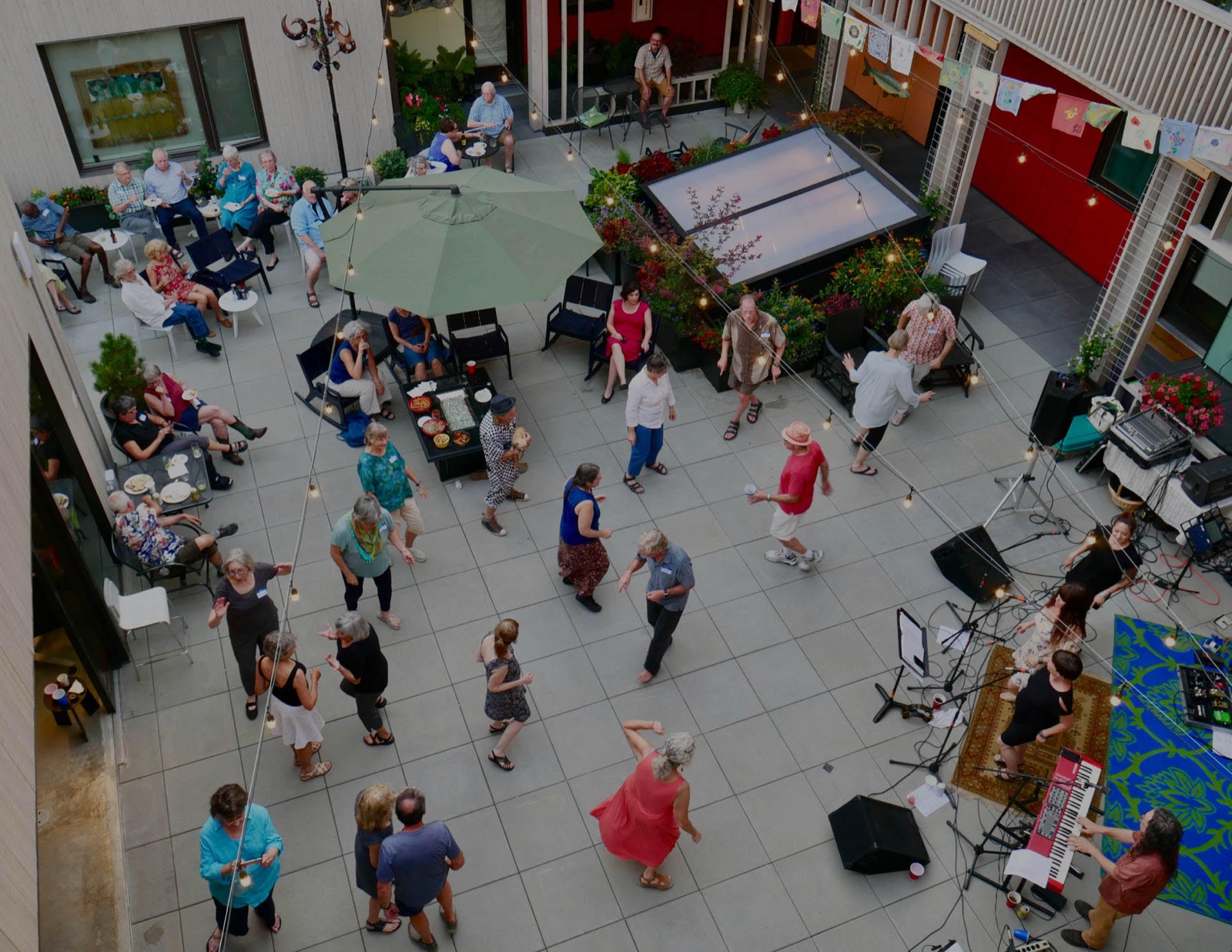 Residents of PDX Commons cohousing community in Portland, Oregon, dancing in the courtyard on a summer evening with a live band and string lights